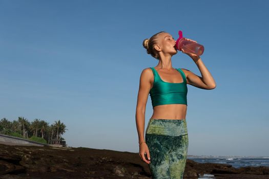 beautiful woman drinking water on the beach. bali