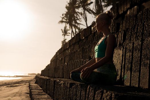 beautiful woman in green sportwear meditating outdoors. bali