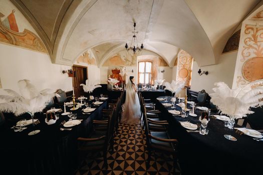 A stylish bride in a wedding dress in the interior of a restaurant decorated with feathers on the tables.