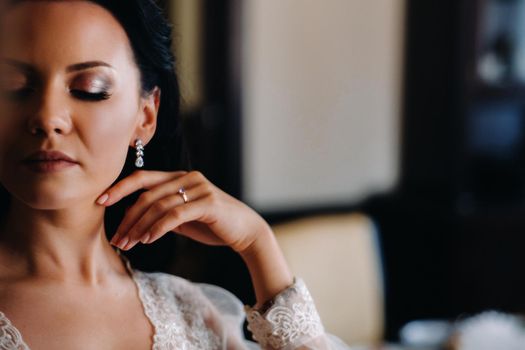 the bride, dressed in a boudoir transparent dress and underwear, stands at home in the morning.