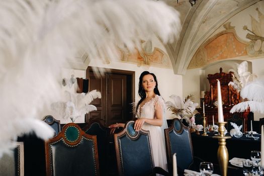 A stylish bride in a wedding dress in the interior of a restaurant decorated with feathers on the tables.