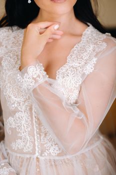 the bride, dressed in a boudoir transparent dress and underwear, stands at home in the morning.