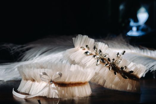 Two white garters of the bride are lying on the table.