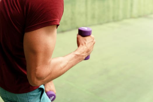 man in sportwear boxing with purple dumbbells. bali