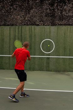 man in red sportwear playing tennis. bali