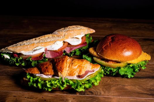 composition of sandwiches with salami and vegetables on a wooden surface