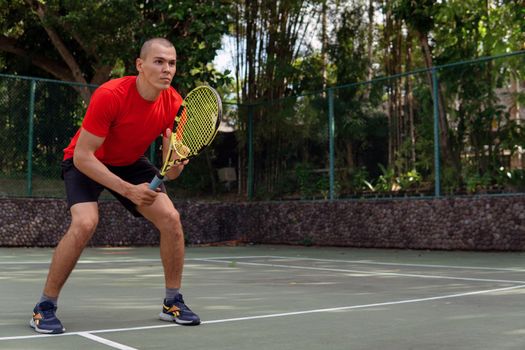 man in red sportwear playing tennis. bali