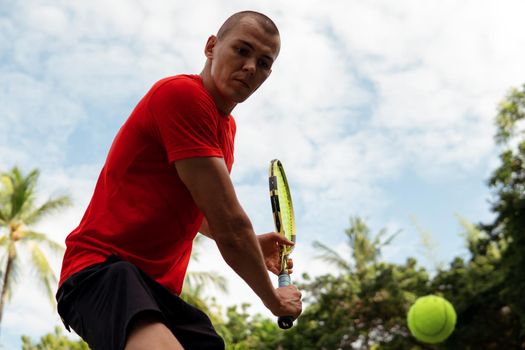 man in red sportwear playing tennis. bali