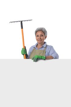 Mature asian woman gardener with rake standing behind blank banner with empty copy space for text isolated on white background