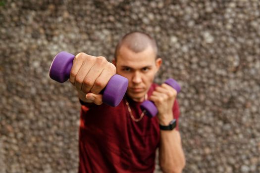 man in sportwear boxing with purple dumbbells. High quality photo