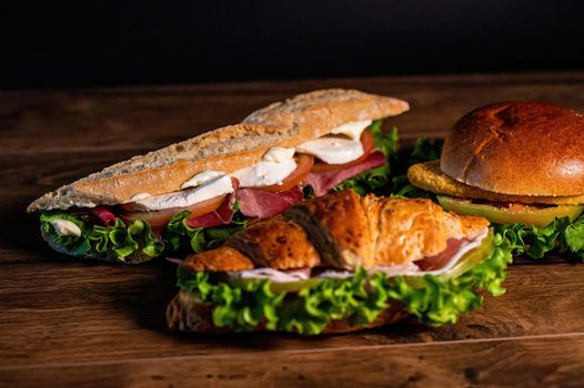 composition of sandwiches with salami and vegetables on a wooden surface