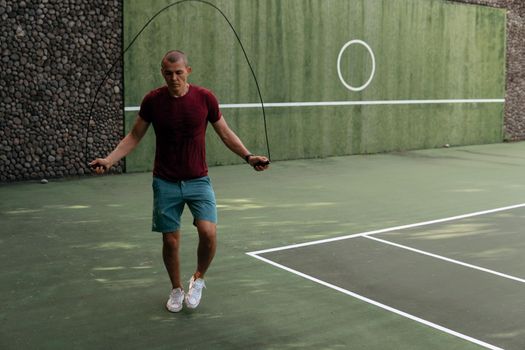 man jumping rope on the tennis court. bali