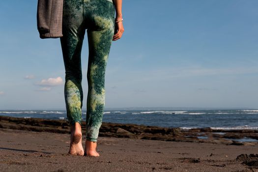 beautiful girl walking on the beach with yoga mat. bali