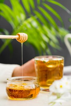 front view woman holding glass with tea honey dipper. High resolution photo