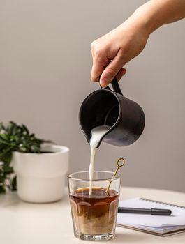 person pouring cream coffee glass. High resolution photo