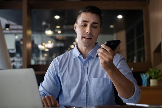 American employee talking with speaker phone and video call by smartphone in home office. Business financial concept