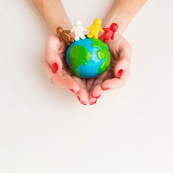 top view hands holding globe with people figurines. High resolution photo