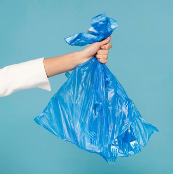 woman holding blue plastic trash bag. High resolution photo