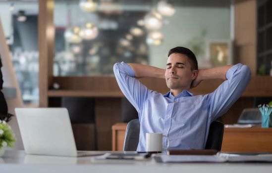 Relaxed calm caucasian businessman resting sit at office desk after working for financial with laptop computer