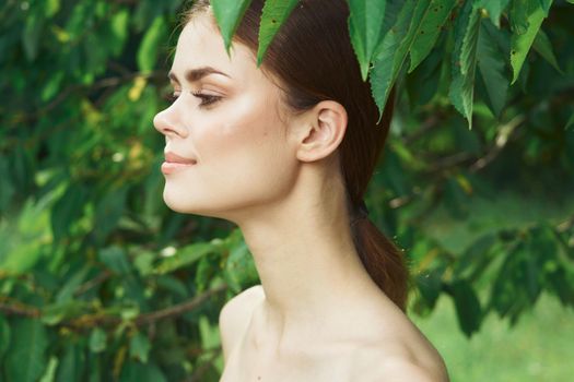 portrait of a woman skin care bare shoulders green leaves nature cropped view. High quality photo