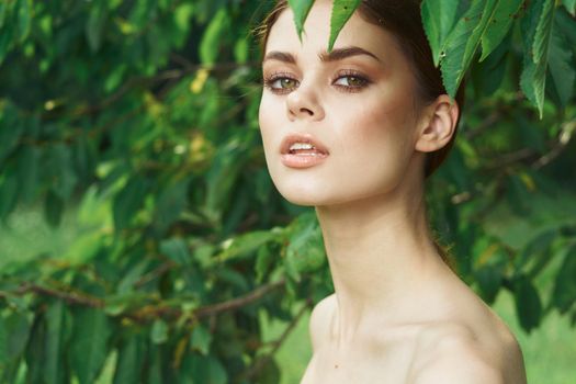 portrait of a woman attractive look bare shoulders green leaves cropped view. High quality photo