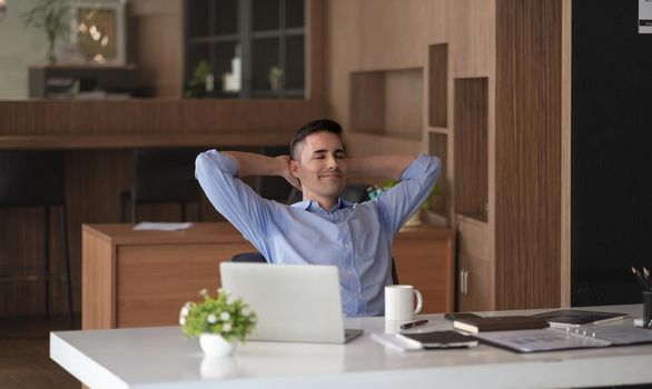 Relaxed calm caucasian businessman resting sit at office desk after working for financial with laptop computer
