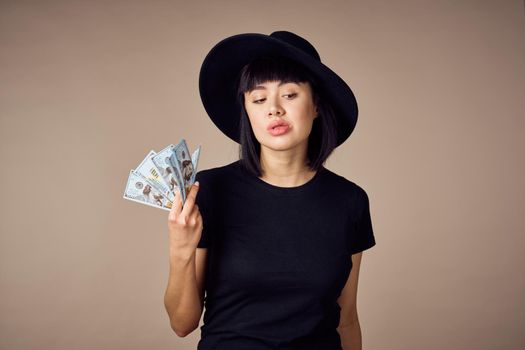 woman in a black t-shirt a wad of money dollars payment beige background. High quality photo