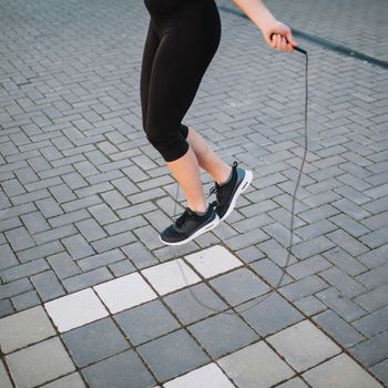 crop woman jumping with rope street. High resolution photo