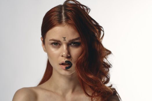 pretty woman with zodiac sign on her face red hair close-up. High quality photo