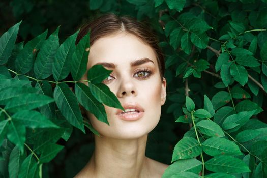 smiling woman skin care bare shoulders green leaves nature close-up. High quality photo