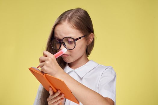 schoolgirl with textbook in hands learning childhood yellow background. High quality photo