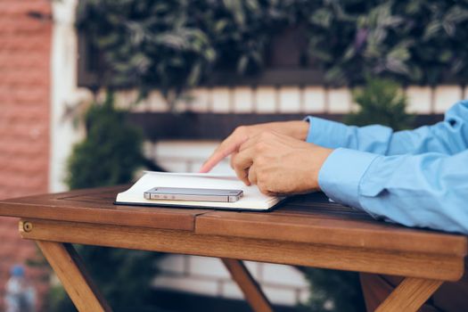 A man sits at a table in a summer cafe documents telephone communication. High quality photo