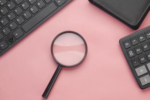 laptop, notepad and magnifying glass on table..