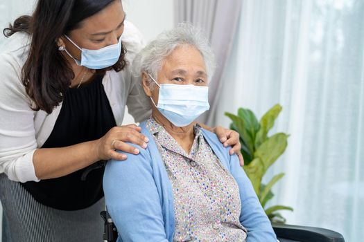 Caregiver help Asian senior or elderly old lady woman sitting on wheelchair and wearing a face mask for protect safety infection Covid-19 Coronavirus.