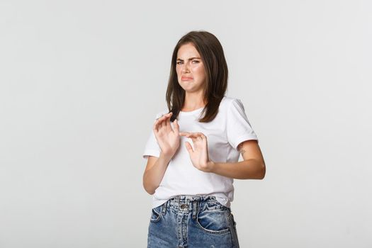 Disgusted young brunette girl grimacing and showing stop gesture, refuse awful disgusting thing.