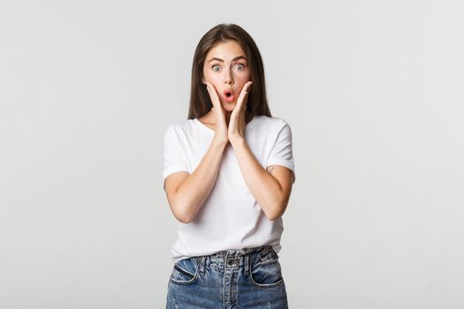 Portrait of surprised and amused brunette girl looking wondered, gasping impressed.