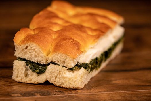 stuffed focaccia with cold cuts and vegetables on a wooden surface