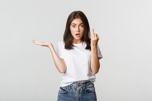 Confused and pissed-off brunette girl arguing about wedding, showing finger without ring.