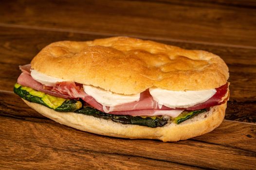 stuffed focaccia with cold cuts and vegetables on a wooden surface