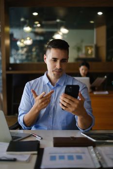 Online video conference and Digital meeting. American Businessman discussing with customer by video call on smartphone in office