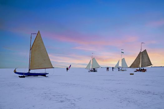 Ice sailing on the Gouwzee in winter in the Netherlands at sunset
