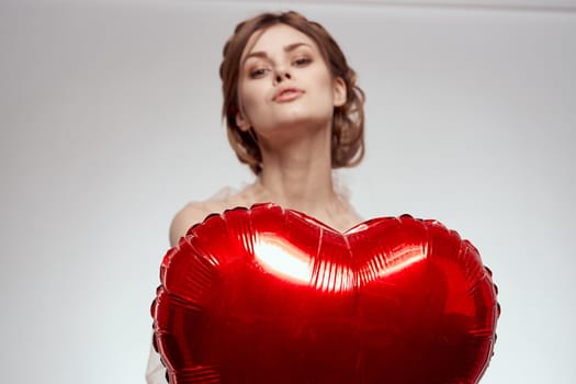 beautiful woman red heart in the hands of the balloon light background. High quality photo