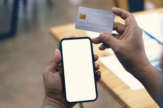 Hands holding smartphone blank screen and credit card