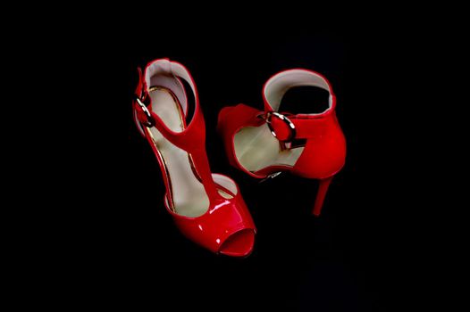 red patent leather sandal for the summer season on a black background