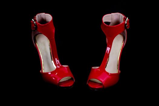 red patent leather sandal for the summer season on a black background