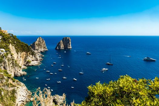 Beautiful panorama of small bay full of small ships and boats next to 
Faraglioni di Mezzo
 and Capri island 