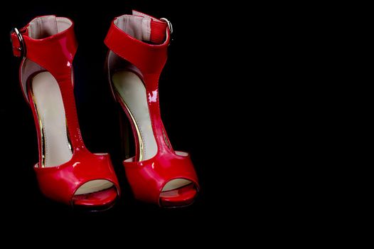 red patent leather sandal for the summer season on a black background