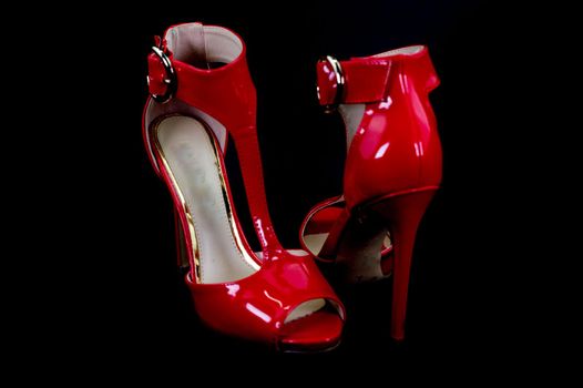 red patent leather sandal for the summer season on a black background