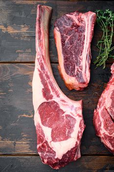 Various cuts of meat dry aged beef set, tomahawk, t bone or porterhouse and club steak, on old dark wooden table background, top view flat lay, with copy space for text
