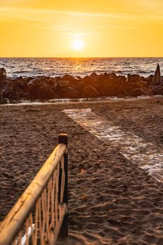 Beautiful sunset with sun over Ischia island over Tyrrhenian Sea and small beach